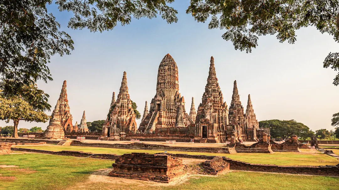 Historische Tempelruinen mit spitzen Türmen in einer grünen Landschaft. Ayutthaya, Zentralthailand, Thailand.

