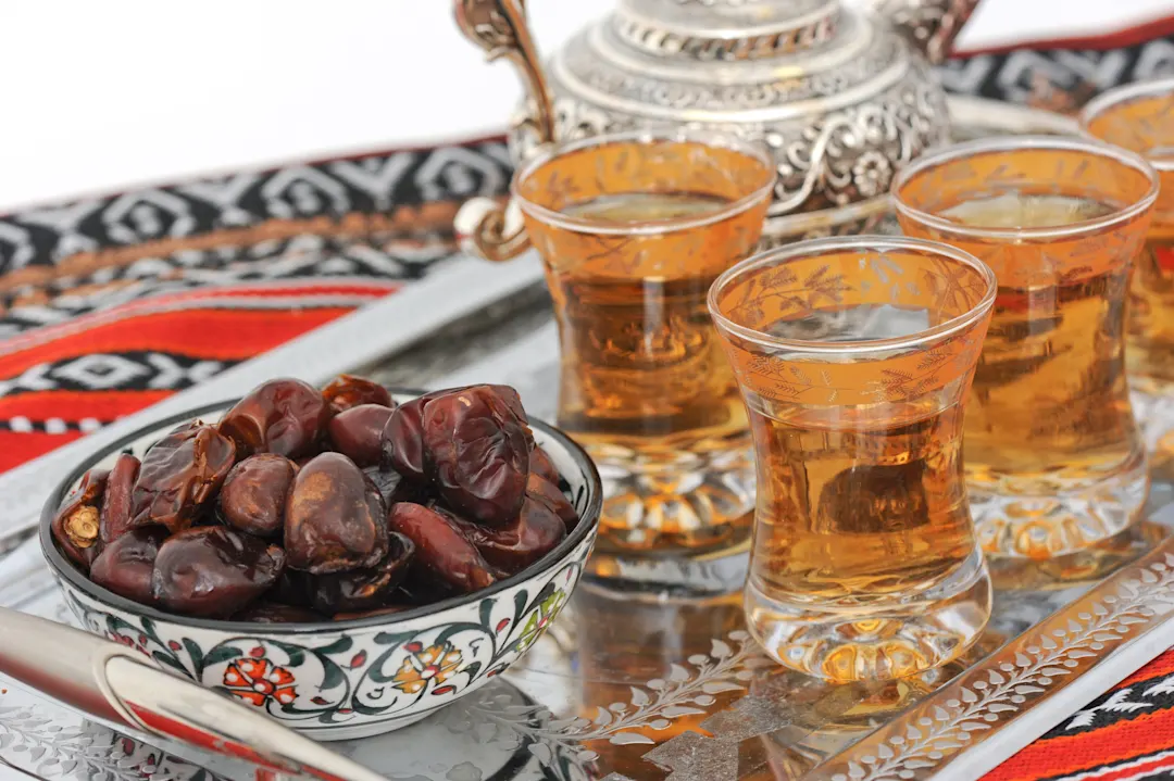 Traditionelle Erfrischungen in Saudi-Arabien Eine Schale mit Datteln und vier Teegläsern mit Minztee auf einem silbernen Tablett
