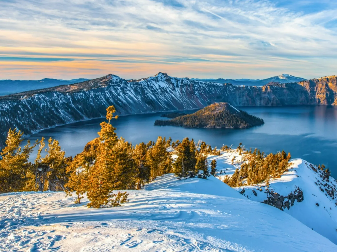 Schneebedeckte Berge mit Blick auf einen tiefblauen Kratersee bei Sonnenuntergang, Oregon, USA. 