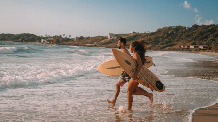 Jeune couple faisant du surf sur une plage au Brésil.

