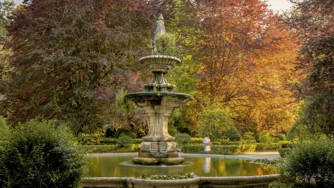 Jardim Botanico, Coimbra, Portugal Blick auf einen alten Brunnen umgeben von Bäumen und Büschen im botanischen Garten von Coimbra