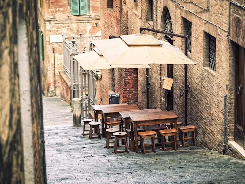 Siena, Toskana, Italien Ein Café mit Tischen und Stühlen in einer engen Gasse, Siena, Toskana, Italien.