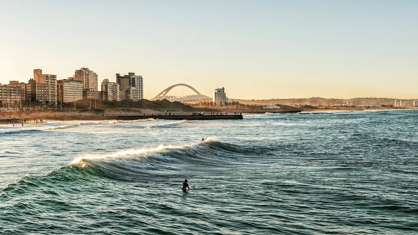 Durban, KwaZulu-Natal, Südafrika Surfer auf einer Welle vor der Skyline von Durban. Durban, KwaZulu-Natal, Südafrika.