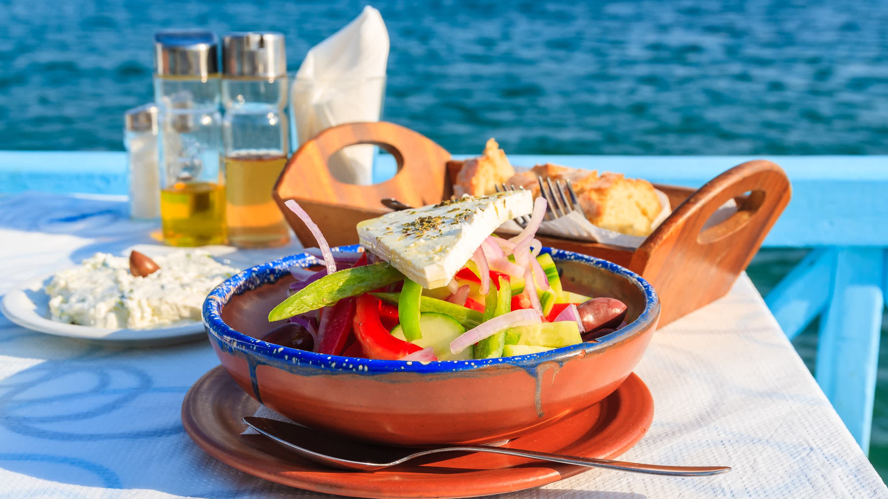 Griechischer Salat am Tisch in griechischen Taverne mit blauen Meerwasser im Hintergrund die Insel Samos, Griechenland

