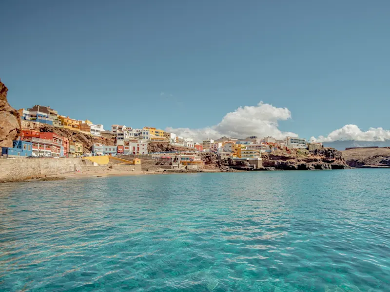 Pittoreske Küstenstadt, bunte Gebäude, türkisfarbenes Meer, blauer Himmel, Gran Canarien, Spanien.