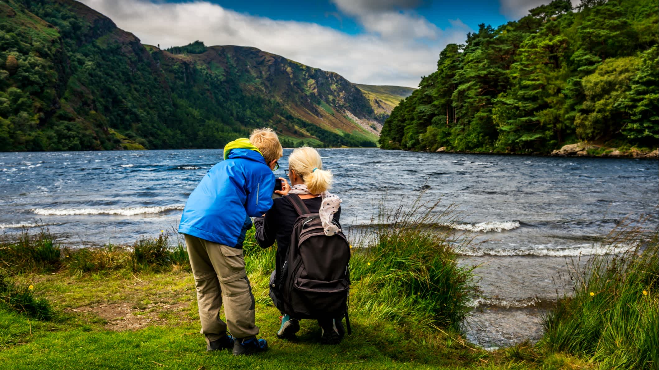 Mutter und Sohn stehen bei einer Wanderung in Irland vor einem See