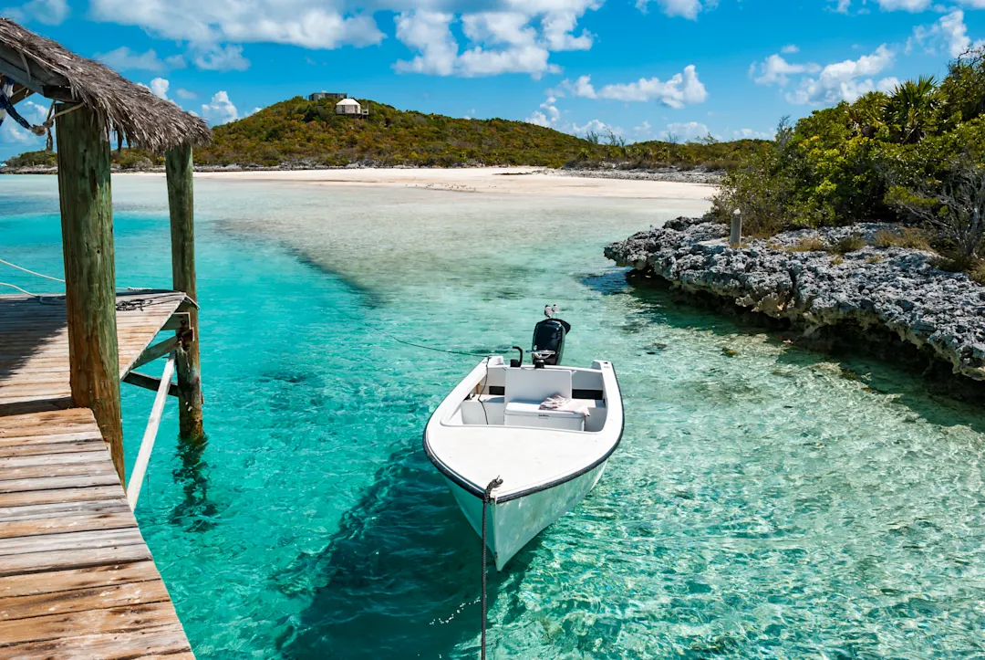Ein kleines Außenbord-Motorboot legte an einem Holzpier im tropischen Paradies der Exuma-Inseln der Bahamas an.

