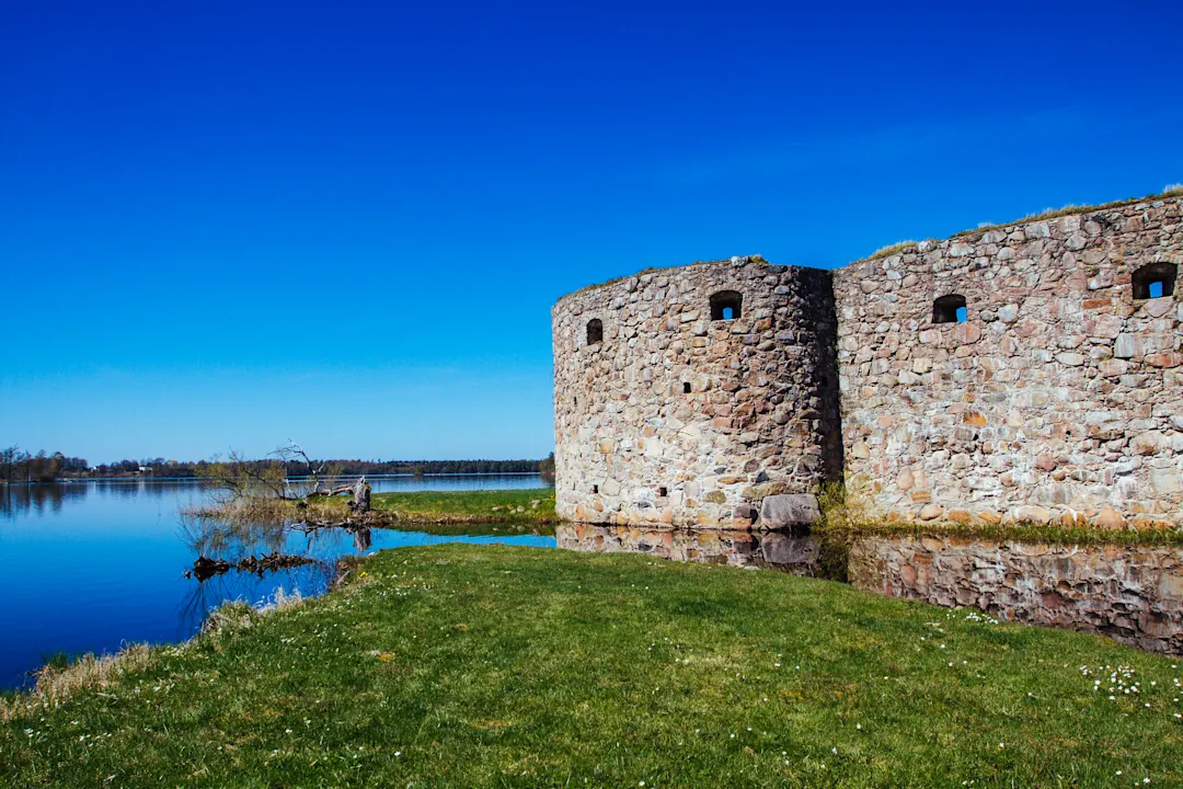 Mittelalterliche Burg am See und am Strand, grüne Rasenflächen
