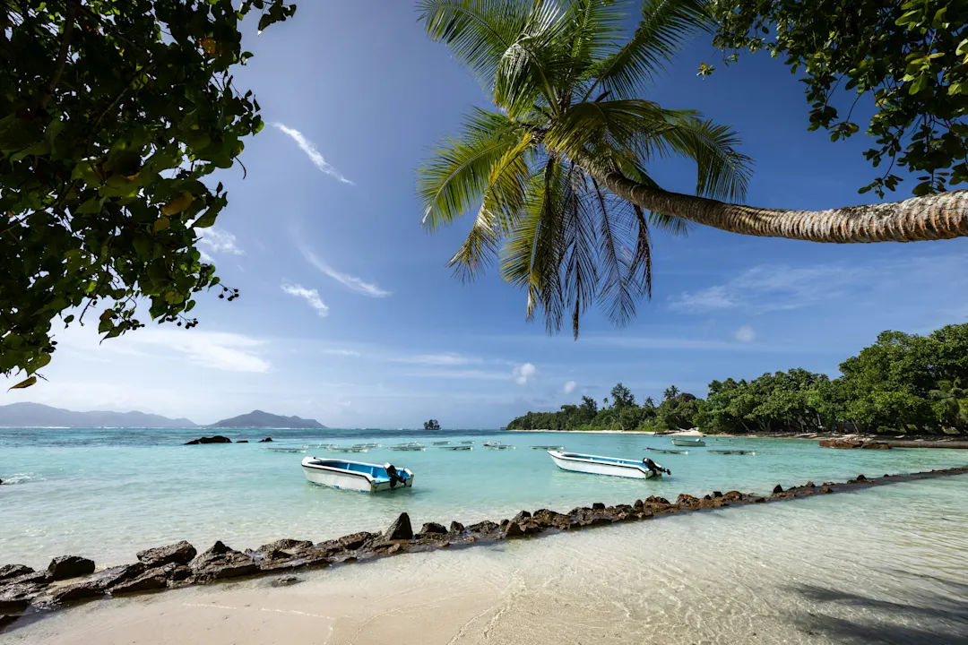 Blick auf die Boote auf dem türkisfarbenen Meer der Seychellen, La Digue