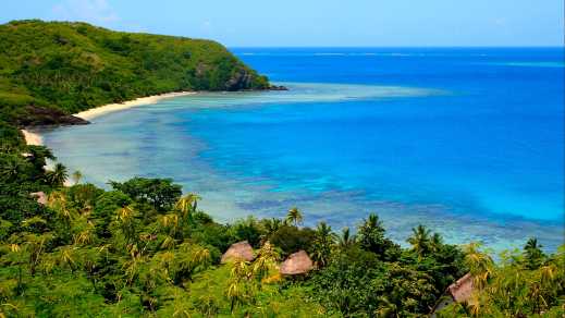 Vue aérienne d'une plage de sable blanc à l'eau turquoise entourée de végétation, aux îles Yasawa, aux Fidji