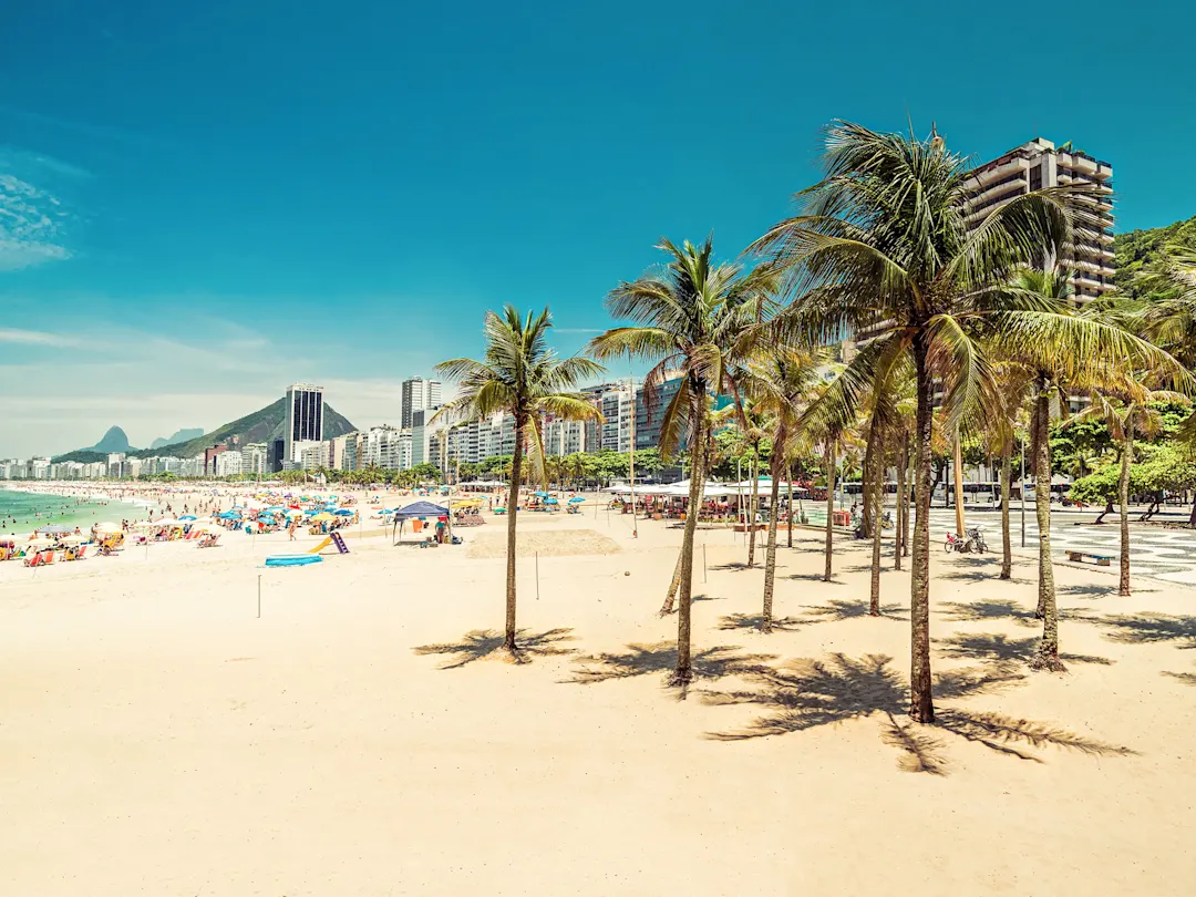 Sandstrand mit Palmen und Bergen. Copacabana, Rio de Janeiro, Brasilien.