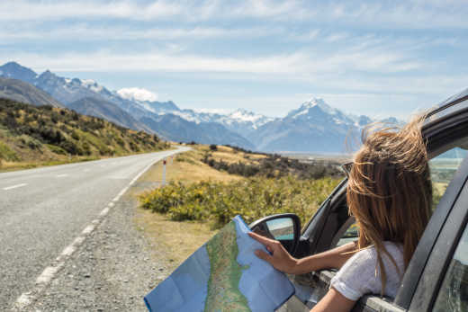 Jeune femme en voiture regardant une carte dans un paysage époustouflant