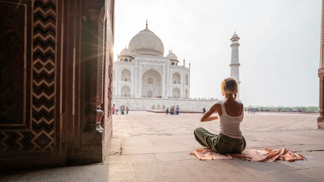 Junge Frau praktiziert Yoga in Indien beim berühmten Taj Mahal bei Sonnenaufgang.