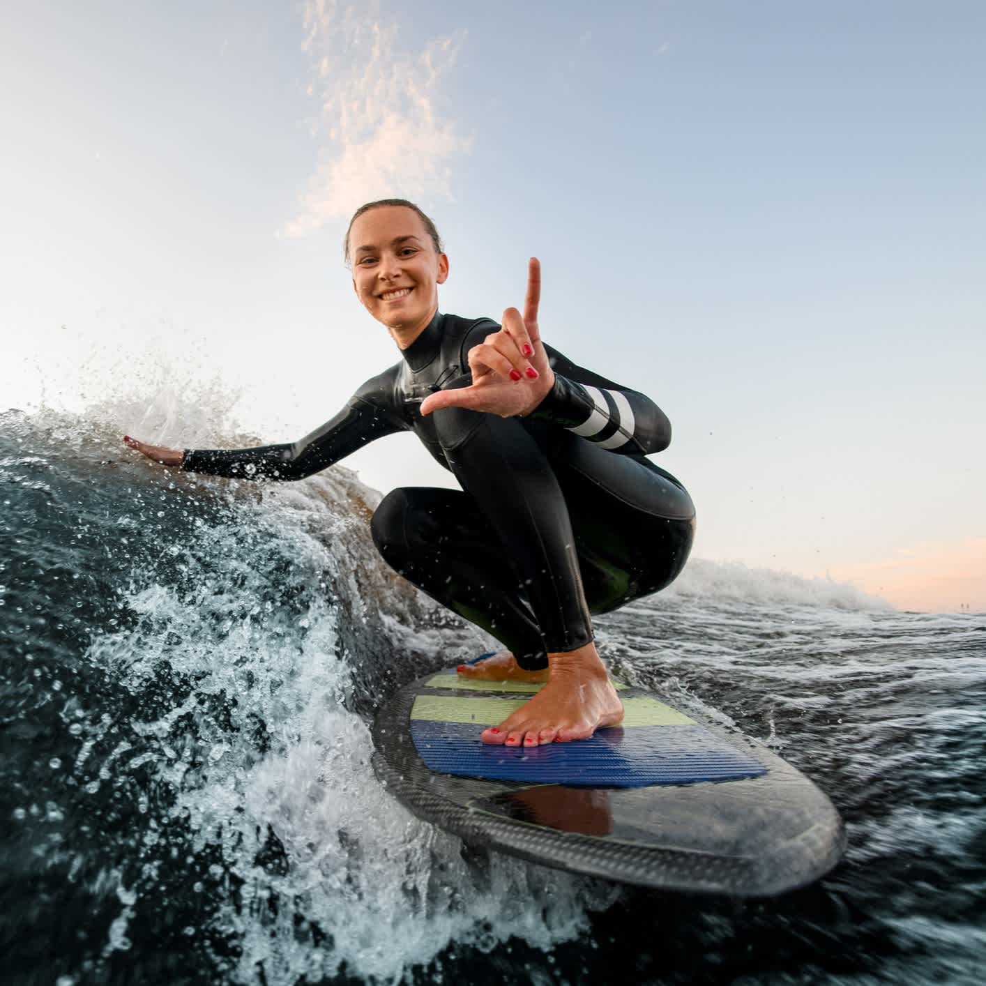 Surferin hockt im Wasser auf einem Surfbrett