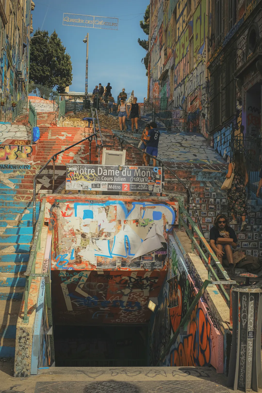 Bunte Treppe im Quartier des Créateurs in Marseille mit Graffiti-Wänden und Besuchern unter blauem Himmel.