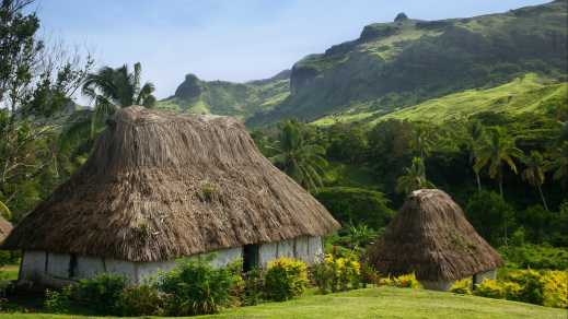 Vue sur des maisons traditionnelles dans un paysage verdoyant, aux îles Fidji.