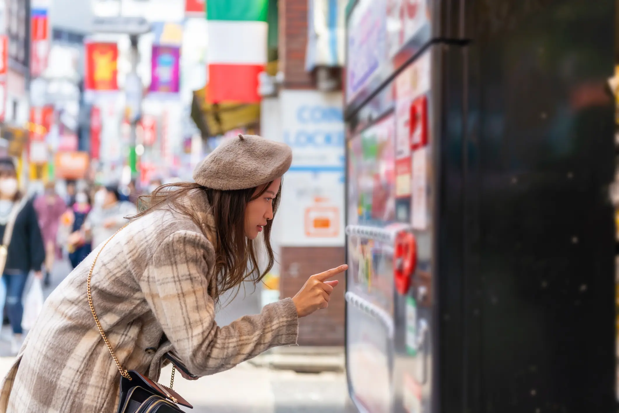 Asiatische Frau, die Getränke am Automaten im Stadtteil Shibuya, Tokio, Japan, kauft.