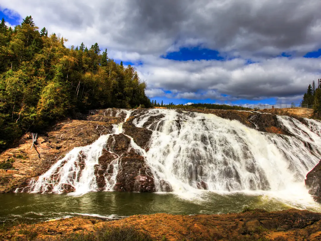 Wasserfall inmitten von Wäldern unter bewölktem Himmel. Québec, Québec, Kanada.
