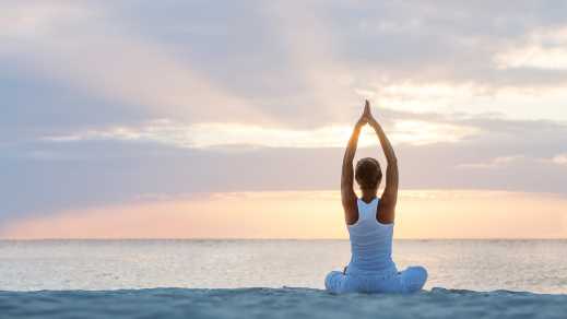Eine Frau übt Yoga an der Küste

