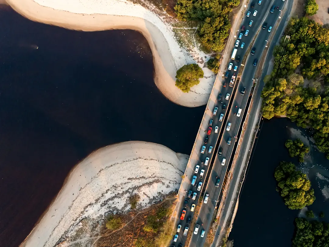 Luftaufnahme einer Brücke mit Verkehr über einen dunklen Fluss. Dar es Salaam, Tansania.