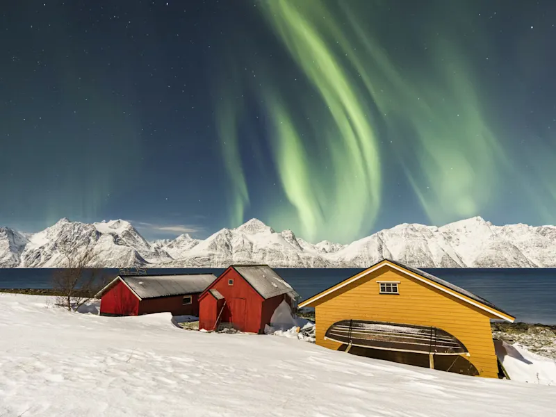 Nordlichter über roten und gelben Häusern in Tromsø, Norwegen.
