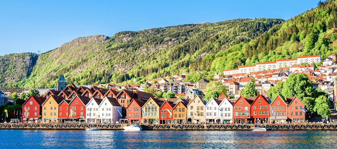 Bunte Häuser am Hafen von Bergen, Norwegen, mit Bergen im Hintergrund.
