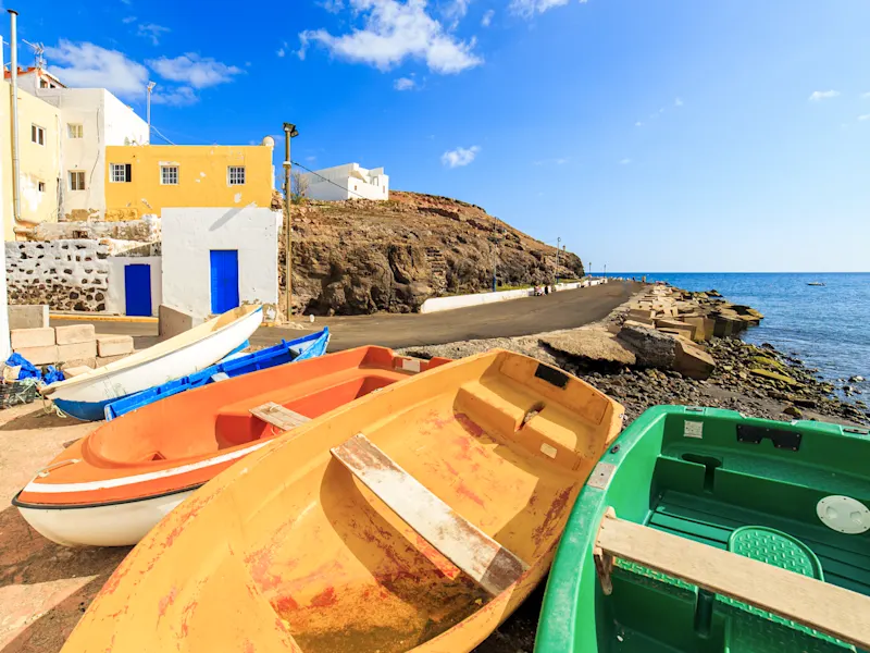Spanien, Kanarische Inseln, Lanzarote, El Golfo Bunt bemalte Fischerboote am Ufer eines kleinen Dorfes. El Golfo, Lanzarote, Spanien.