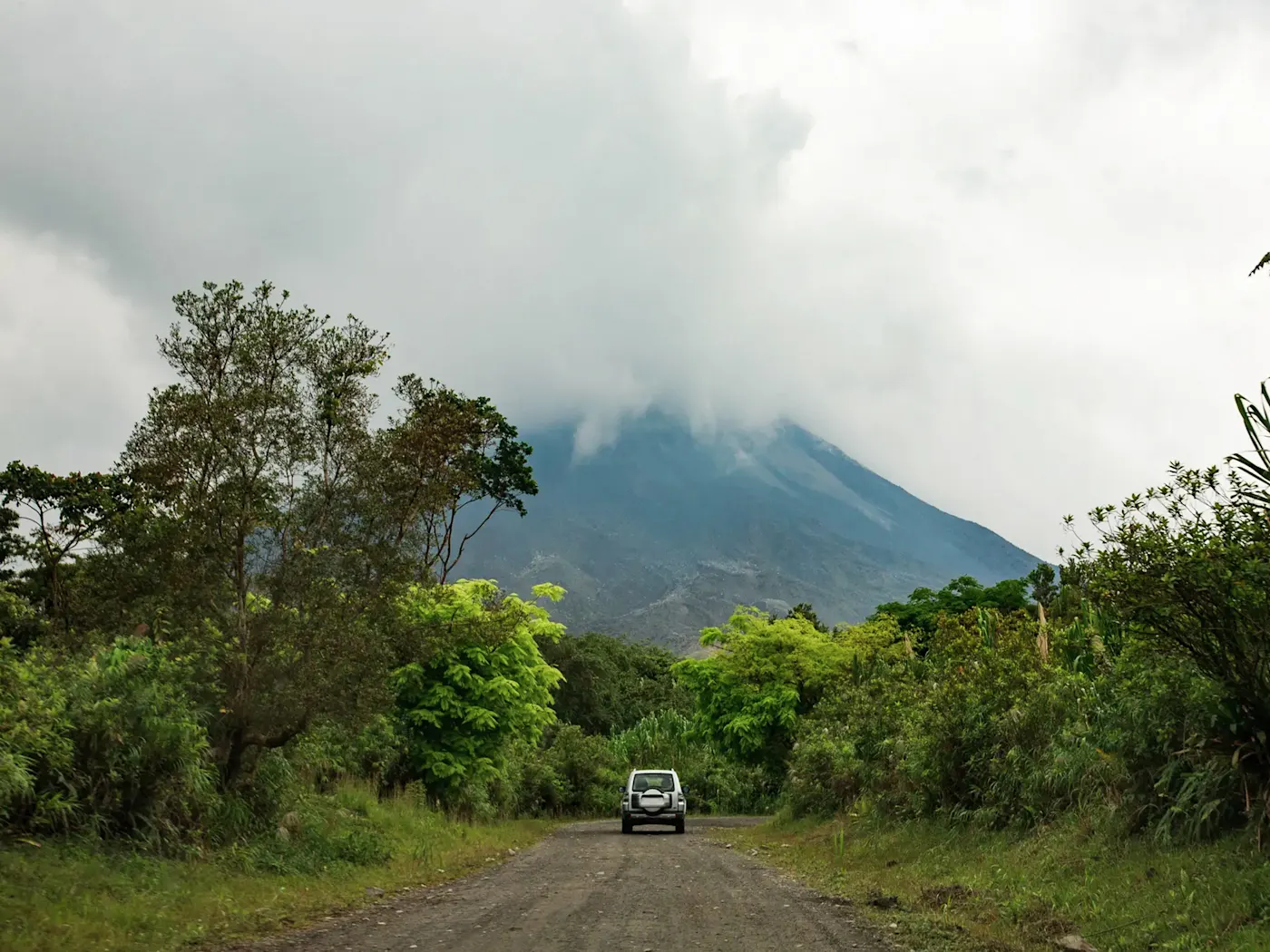 Costa Rica, Alajuela, La Fortuna Auto auf Schotterstraße mit Vulkanblick, La Fortuna, Alajuela, Costa Rica.
