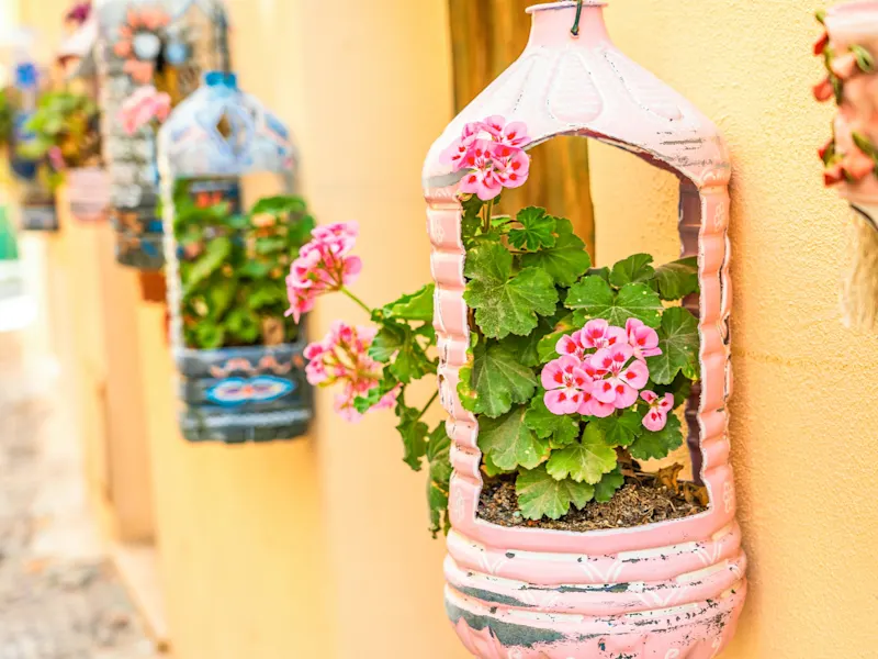 Alghero, Sardinien, Italien Bunte Blumenkästen aus Plastikflaschen an einer Wand in Alghero, Sardinien, Italien.