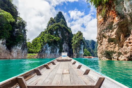 Vue des falaises verdoyantes et de l'eau turquoise depuis un bateau en bois, Parc national de Khao Sok, en Thaïlande