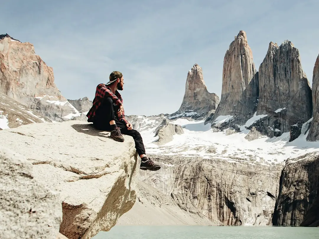 Wanderer sitzt auf Felsen mit Bergen im Hintergrund. El Chaltén, Santa Cruz, Argentinien.
