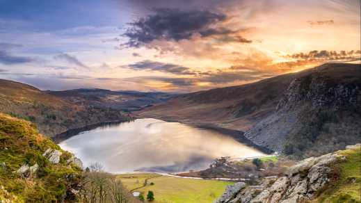 Le coucher de soleil sur le lac Guinness entouré de montagnes, à Wicklow, en Irlande.