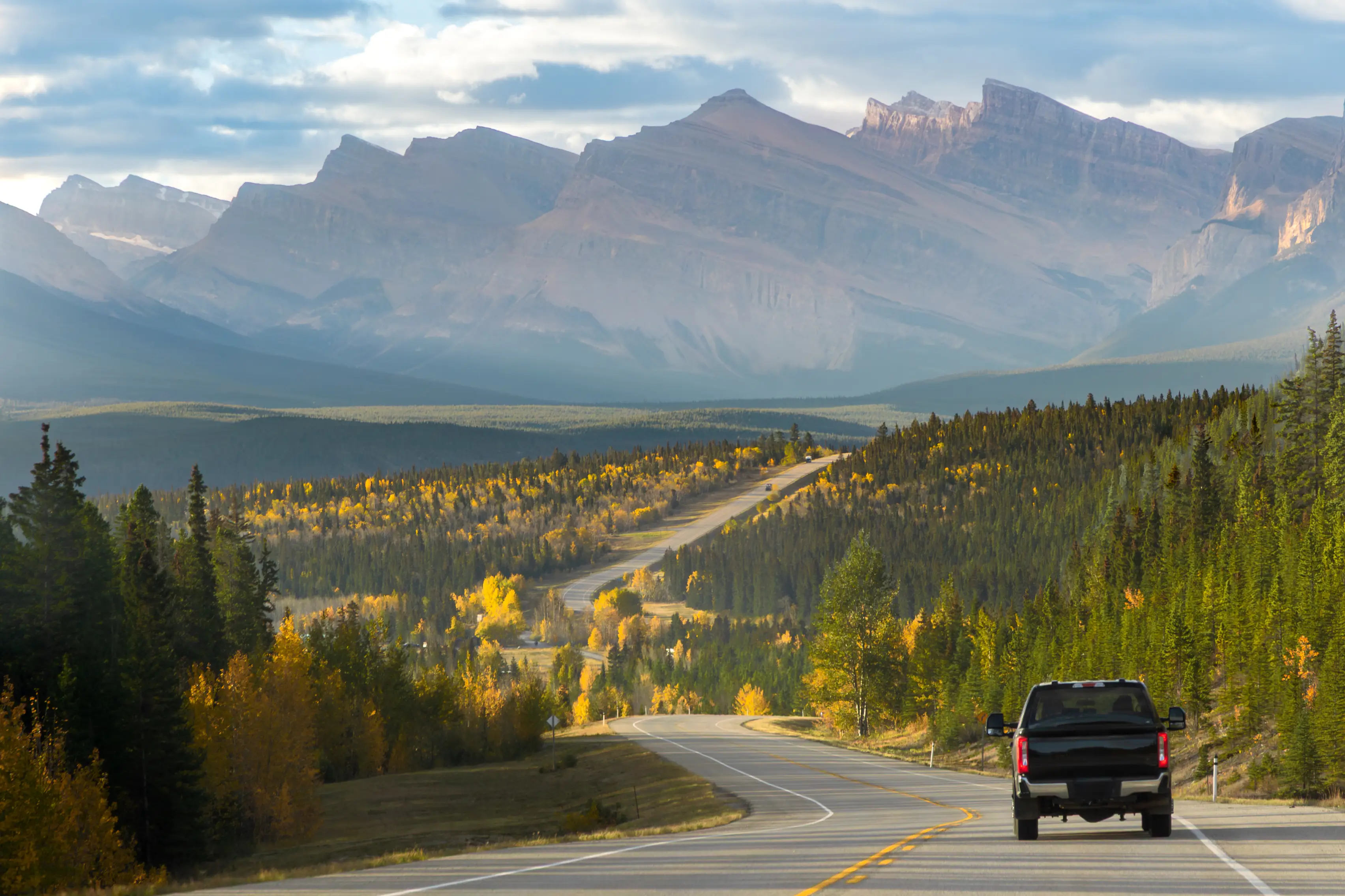 Pickup-Truck fährt auf der Autumn Road in Alberta in Richtung Bergkette