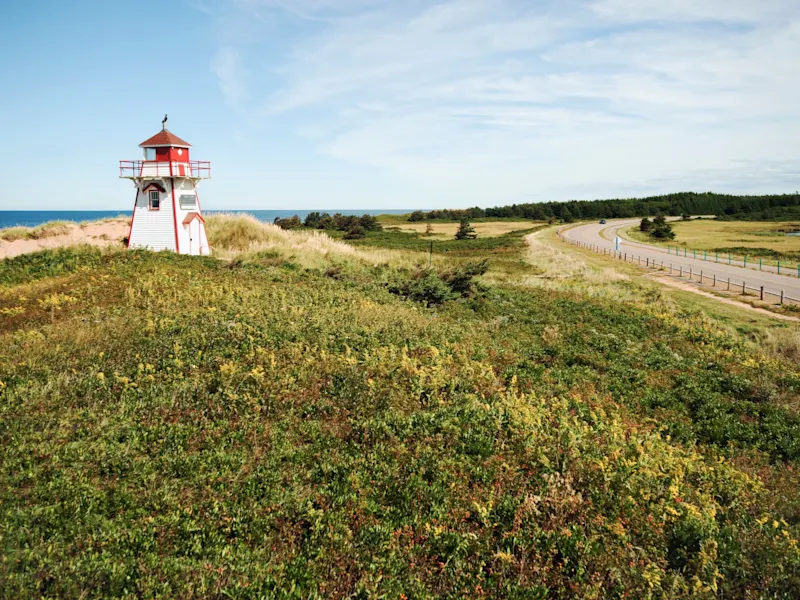 Prince Edward Island, Prince Edward Island, Kanada Landschaft mit kleinem Leuchtturm inmitten von Dünen und Vegetation nahe einer Straße. Prince Edward Island, Prince Edward Island, Kanada.