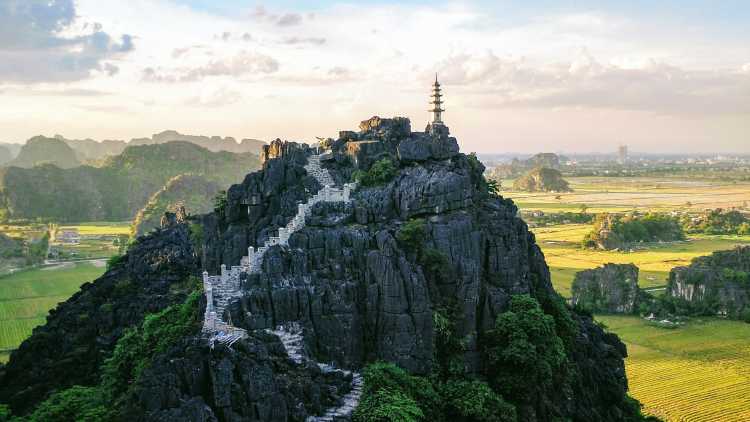 Impressionnante vue aérienne sur un temple perché tout en haut du Mont des Provinces de Ninh Bình. Un spectacle qui vous coupera le souffle pendant votre voyage au Vietnam.