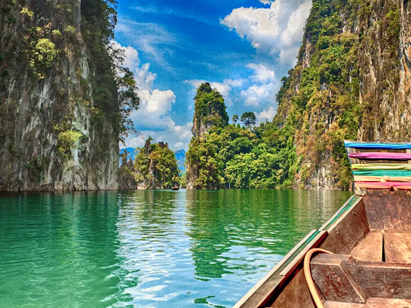 Thailand, Khao Sok Nationalpark, Cheow Lan Lake Boot auf smaragdgrünem See zwischen Karstfelsen. Cheow Lan Lake, Khao Sok Nationalpark, Thailand.