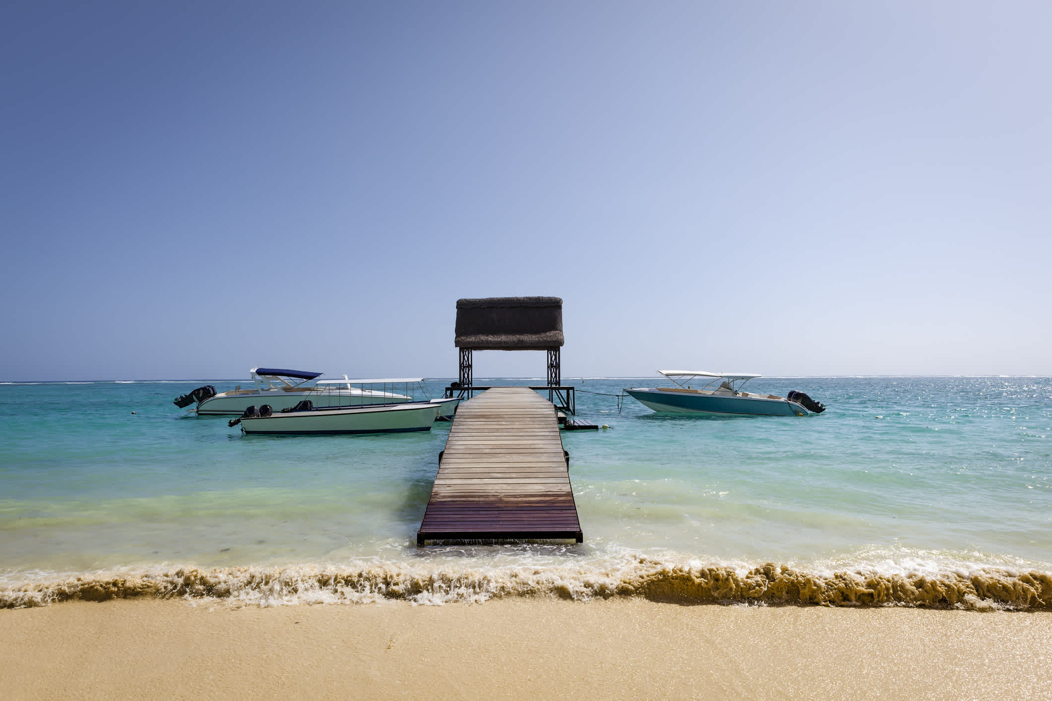 Bateaux sur l'eau près d'un ponton en bois sur la plage de Trou-aux-Biches, Île Maurice