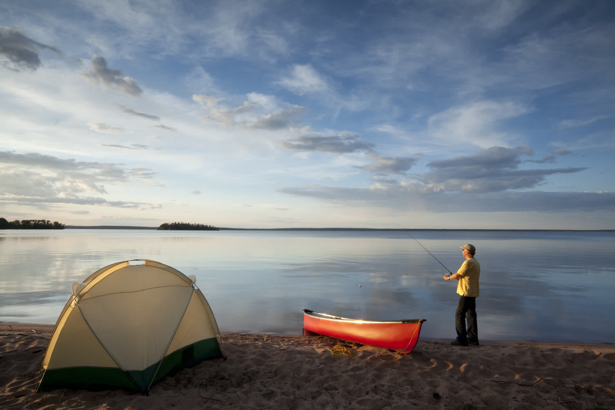 Camping avec un canoë qui repose sur la rive du lac.
