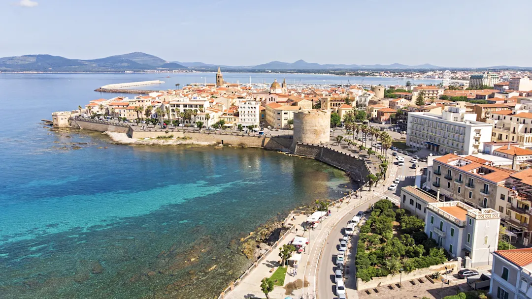 Blick auf Alghero mit der Altstadt, dem Hafen und dem türkisfarbenen Meer, Sardinien, Italien.
