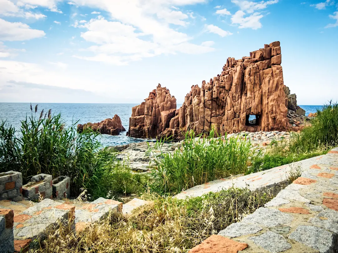 Rote Felsformationen am Meer mit natürlichem Tor. Rocce Rosse, Arbatax, Sardinien, Italien.