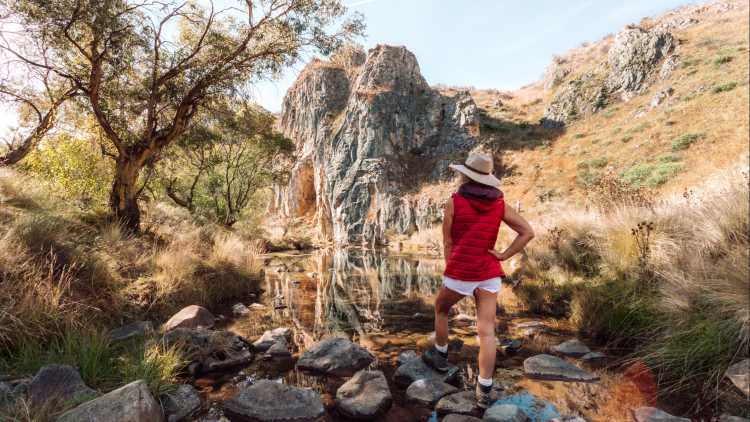 Eine Frau vor der Höhle auf Caves Creek, Blue Mountains, Australia. 