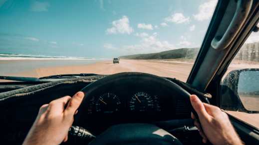Uitzicht over het stuur terwijl je over het strand van Fraser Island rijdt