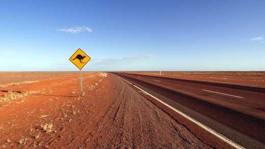 Panneau routier représentant un kangourou au bord de l'autoroute déserte de Stuart, en Australie.