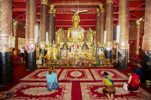Découvrez l'intérieur majestueux du temple Wat Mai Suwannaphumaham et son buddha en or lors de vos vacances à Luang Prabang.