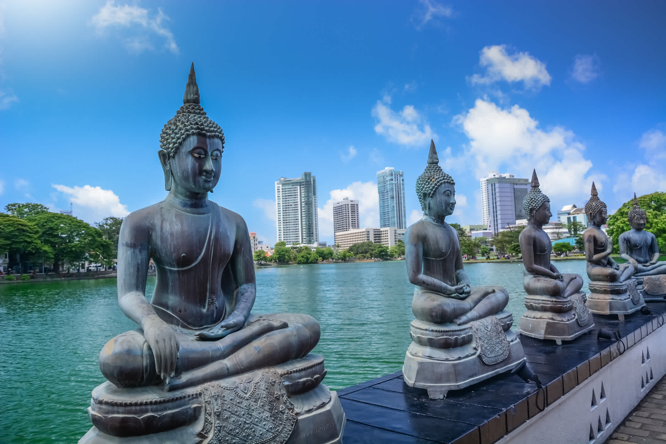 Statues de bouddhas au bord de l'eau avec des gratte-ciel en arrière-plan à Colombo, au Sri Lanka