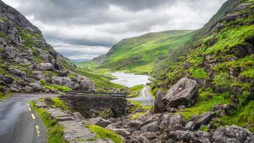 Straße und Steinbrücke mit Blick auf Gap of Dunloe Valley, Ring of Kerry, County Kerry, Irland.

