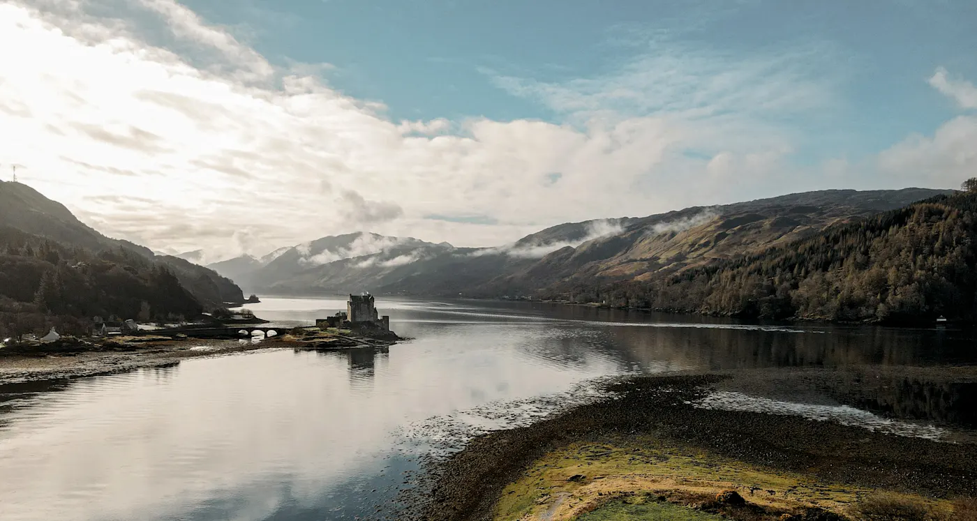 Eilean Donan Castle, Scotland Eilean Donan Castle on a misty morning, situated on a small island where three Scottish lochs meet, surrounded by mountains.