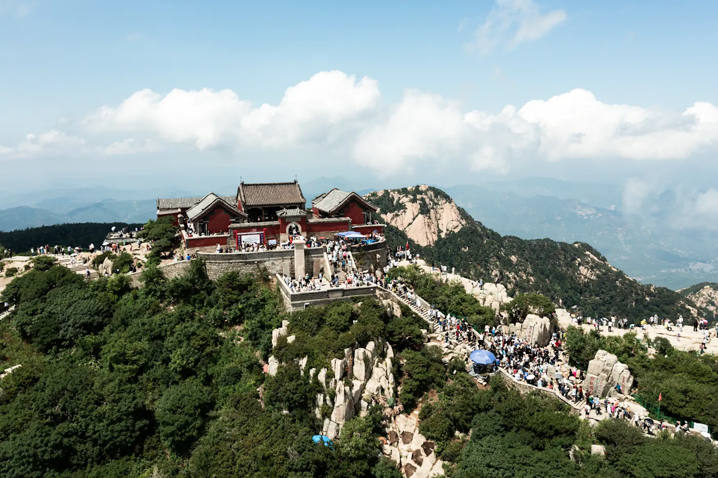 Traditioneller chinesischer Tempel auf dem Gipfel des Taishan-Berges mit Besuchermassen und atemberaubender Aussicht.