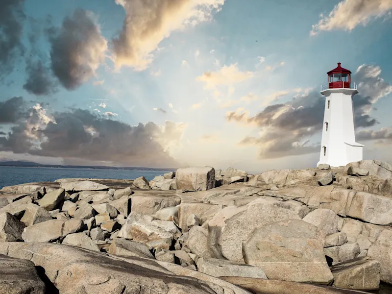 Halifax, Nova Scotia, Kanada, Der ikonische Leuchtturm von Peggy’s Cove bei Sonnenuntergang auf felsigem Gelände. Halifax, Nova Scotia, Kanada.