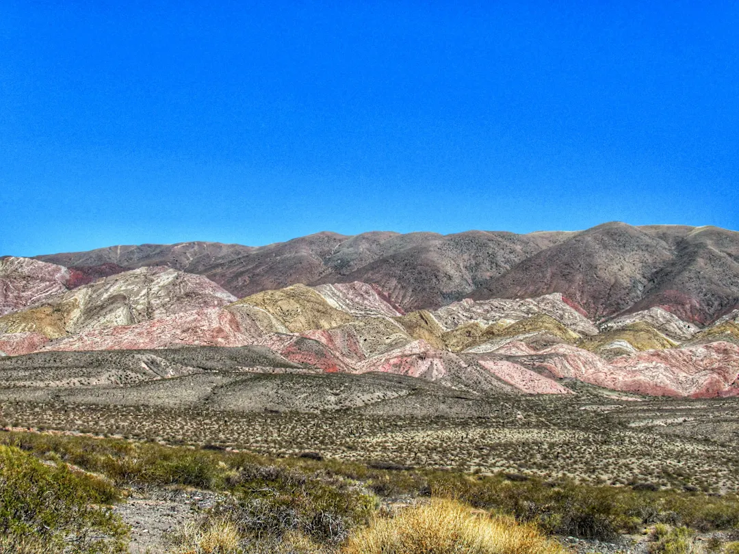 Eine atemberaubende Naturlandschaft mit den wunderschönen, imposanten und farbenprächtigen Bergen der Anden im Herzen der argentinischen Puna an einem sonnigen Tag mit blauem Himmel im Valle Calchaquí, einer Region des Nationalparks Los Cardones